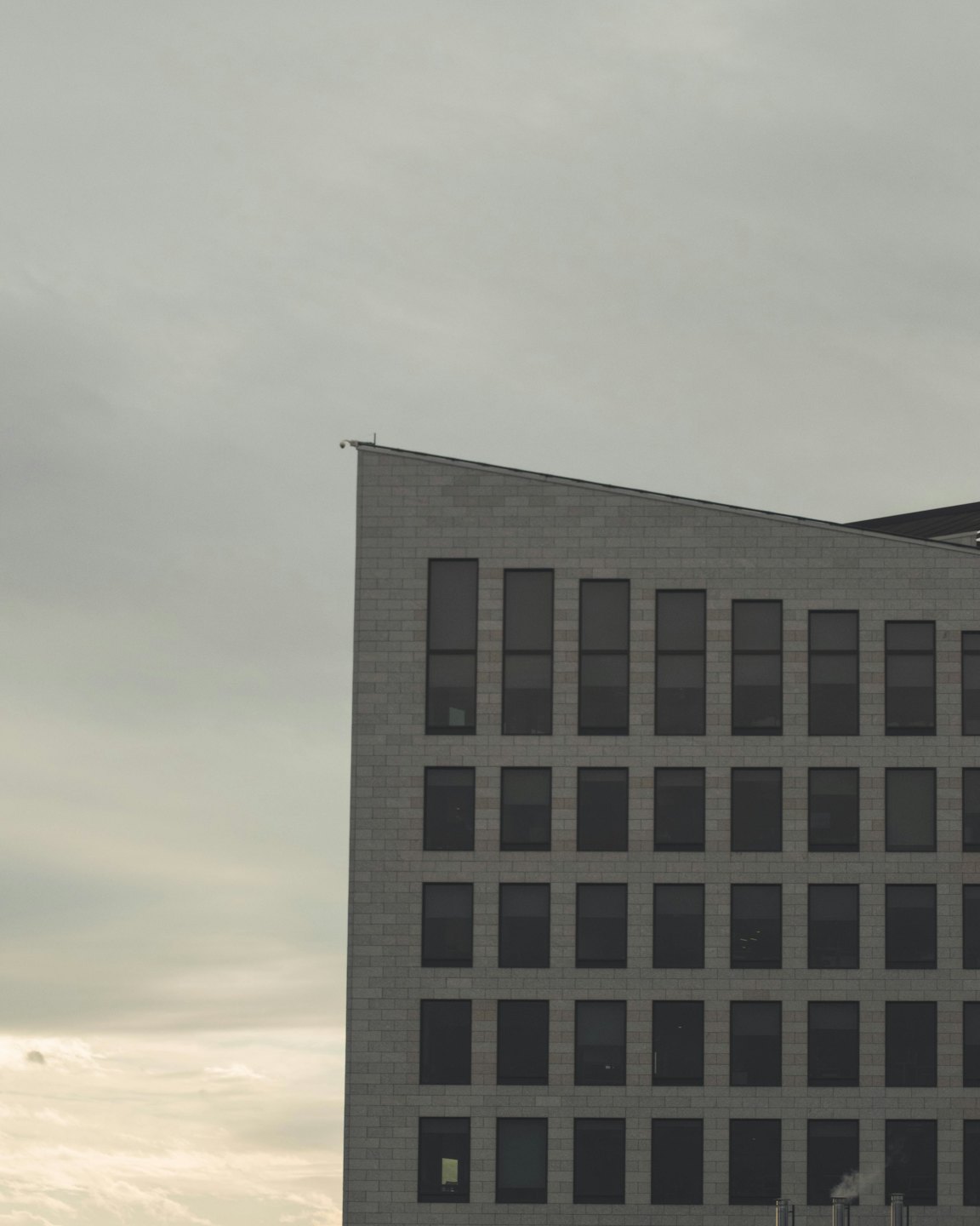 Moderno edificio commerciale in mattoni grigi con tetto spiovente.