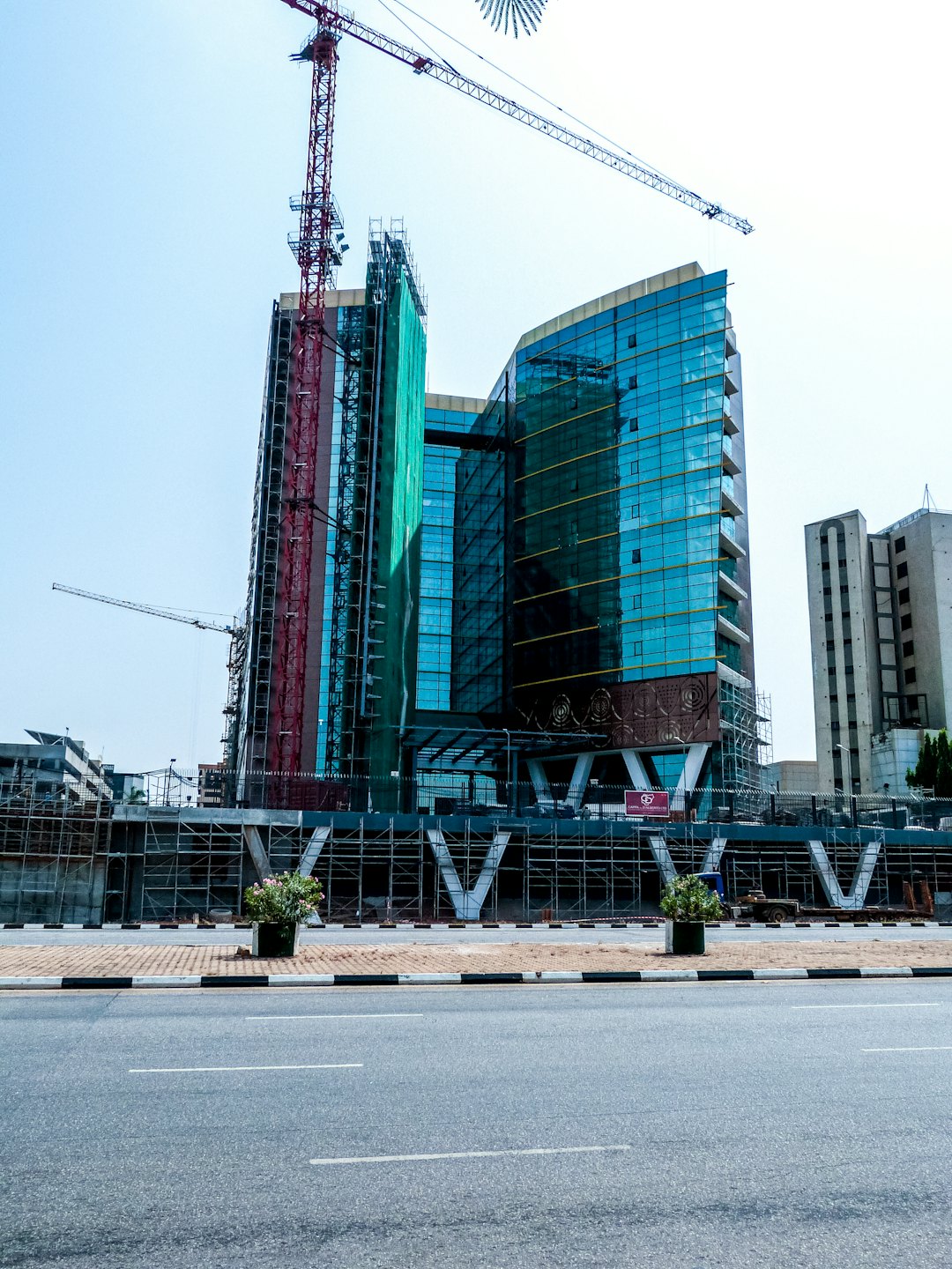 Edificio moderno in costruzione con gru contro il cielo blu.